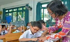 Cô giáo uốn nắn cho học trò từng nét chữ, nết người. Ảnh: Tấn Thạnh/Người Lao Động.