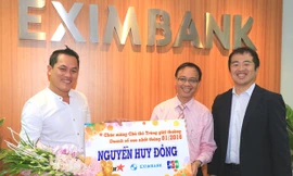 Đại diện Eximbank, ông Nguyễn Hồ Hoàng Vũ – Phó Tổng Giám đốc Eximbank (thứ 2 bên phải) đại diện trao quà và hoa lưu niệm cho khách hàng Nguyễn Huy Đông.