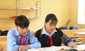 Em Sùng Thanh Tâm (bên phải) ngồi học bài dưới ánh sáng mới của lớp học