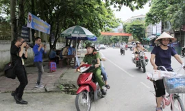 Đại úy Vũ Đức Lợi chở thí sinh Trần Thị Yến đến điểm thi, phía sau có xe chuyên dụng của CSGT hú còi hộ tống Ảnh: Trường Phong 