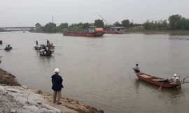 Lực lượng chức năng và người dân vẫn đang tìm kiếm thi thể người vợ bị chìm dưới sông - Ảnh: Hoàng Long