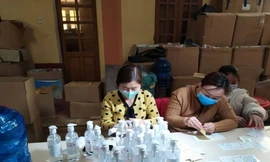 Công an phát hiện công nhân đang dán nhán, gắn tem mác vào chai nước rửa tay giả - Ảnh: CTV