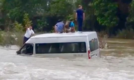 Chiếc xe ô tô chở nhiều khách bị nước cuốn trôi trong sự kinh hãi của mọi người. Ảnh: PV