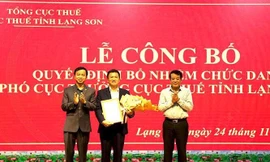 Ông Bùi Minh Bằng (giữa) nhận quyết đinh và hoa chúc mừng của lãnh đạo ngành thuế .Ảnh: T. Dũng 