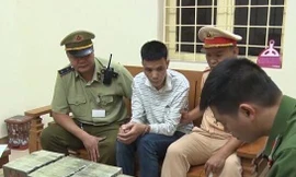 Đối tượng Dần (áo trắng, ngồi giữa) cùng tang vật bị bắt tại khu vực Trạm kiểm soát LN Dốc Quýt. Ảnh: H.S