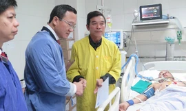 Phó Chủ tịch chuyên trách Uỷ ban ATGT Quốc gia Khuất Việt Hùng động viên bố nạn nhân Ngô Văn Tuấn đang điều trị chấn thương do tai nạn giao thông tại Bệnh viện Việt Đức. 