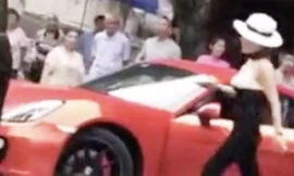 Người phụ nữ đội mũ lái chiếc xe màu đỏ bị ghi hình hành động sỉ nhục và tấn công người đi xe phía sau