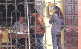 Trong khuôn viên của Phòng PA61, cò L (X) đang ghi tờ khai sau khi đã thỏa thuận với khách. Người phụ nữ đứng bên cạnh cũng là một cò quen thuộc với nhiều người dân đến làm thủ tục cấp hộ chiếu. Ảnh chụp sáng 31-3-2011 Ảnh: N.H