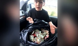 Cậu bé Griffin Steele, 7 tuổi, bên bao tiền lớn cậu tìm thấy gần thùng rác của trạm xăng.