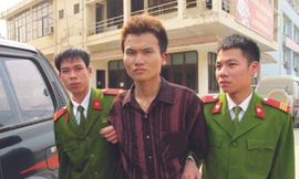 Đối tượng Đỗ Văn Nhuận (giữa) bị dẫn giải ra xe cảnh sát