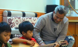 Anh Y Ploi  hướng dẫn chơi đàn ghi-ta cho học trò. Ảnh: N.T