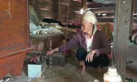Bà Chìu Thị Tài bên chiếc bình ắc quy cũ kỹ