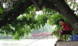 Ngồi ghế nhựa, uống trà đá thản nhiên câu cá ở Hồ Gươm. Ảnh: Trường Phong