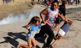 Một gia đình người di cư chạy trốn trong hoảng loạn bởi hơi cay mù mịt