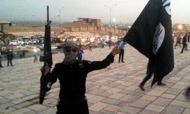 Một tay súng IS vẫy cờ và chĩa súng trên đường phố Mosul (2014)