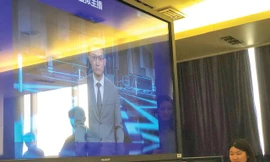 Đại diện Xinhua giới thiệu về người dẫn chương trình tin tức AI (trên màn hình) của hãng tại Bắc Kinh. Ảnh: Thái An 