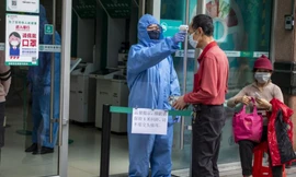 Một nhân viên bảo vệ kiểm tra thân nhiệt của khách hàng vào chi nhánh ngân hàng ở Quảng Châu. (Ảnh: EPA-EFE)