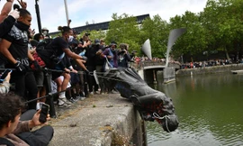 Người biểu tình ở London vứt tượng Edward Colston xuống sông. (Ảnh: CNN)