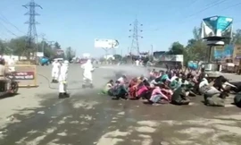 Một nhóm lao động di cư bị phun thuốc diệt trùng sau khi trở về từ thành phố. 