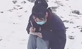 Cô nữ sinh ngồi học bài trên núi phủ đầy tuyết. (Ảnh từ clip)
