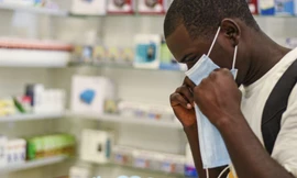 Một người thử đeo khẩu trang y tế tại hiệu thuốc ở Zambia. (Ảnh: AP)