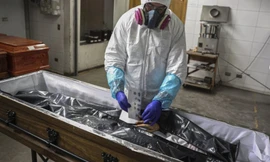 Nhân viên y tế lấy dấu vân tay của một phụ nữ chết vì COVID-19 ở Chile ngày 27/6. (Ảnh: AP)