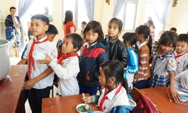 Các em học sinh xếp hàng nhận phần cơm của mình