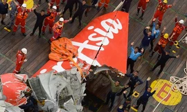 Đội trục vớt đứng cạnh phần đuôi máy bay AirAsia vừa được vớt lên, vẫy trực thăng cứu hộ