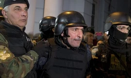 Ông Jose Lopez (giữa) mặc đồ bảo vệ khi bị bắt để phòng trường hợp bị tấn công. Ảnh: AP