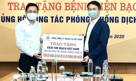 Ông Hồ Lê Nghĩa (bên trái)trao tặng tiền ủng hộ bệnh viện chống covid 19