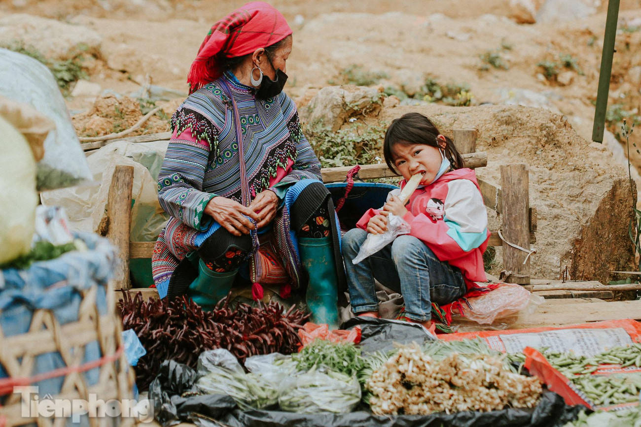 Đứa trẻ ngồi bán hàng cùng mẹ cùng bà.