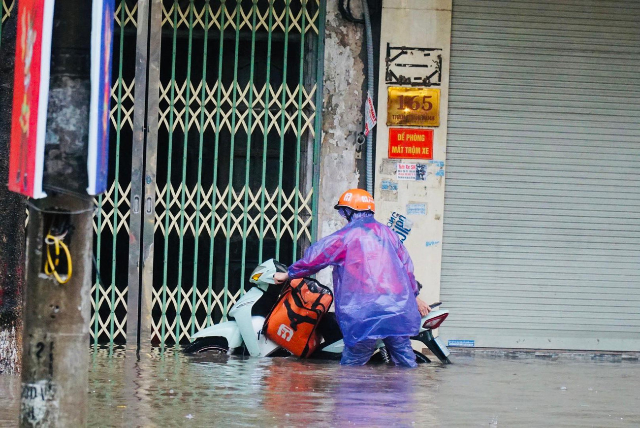 Nhiều người di chuyển xe máy buộc phải xuống dắt xe qua điểm ngập vì không thể di chuyển