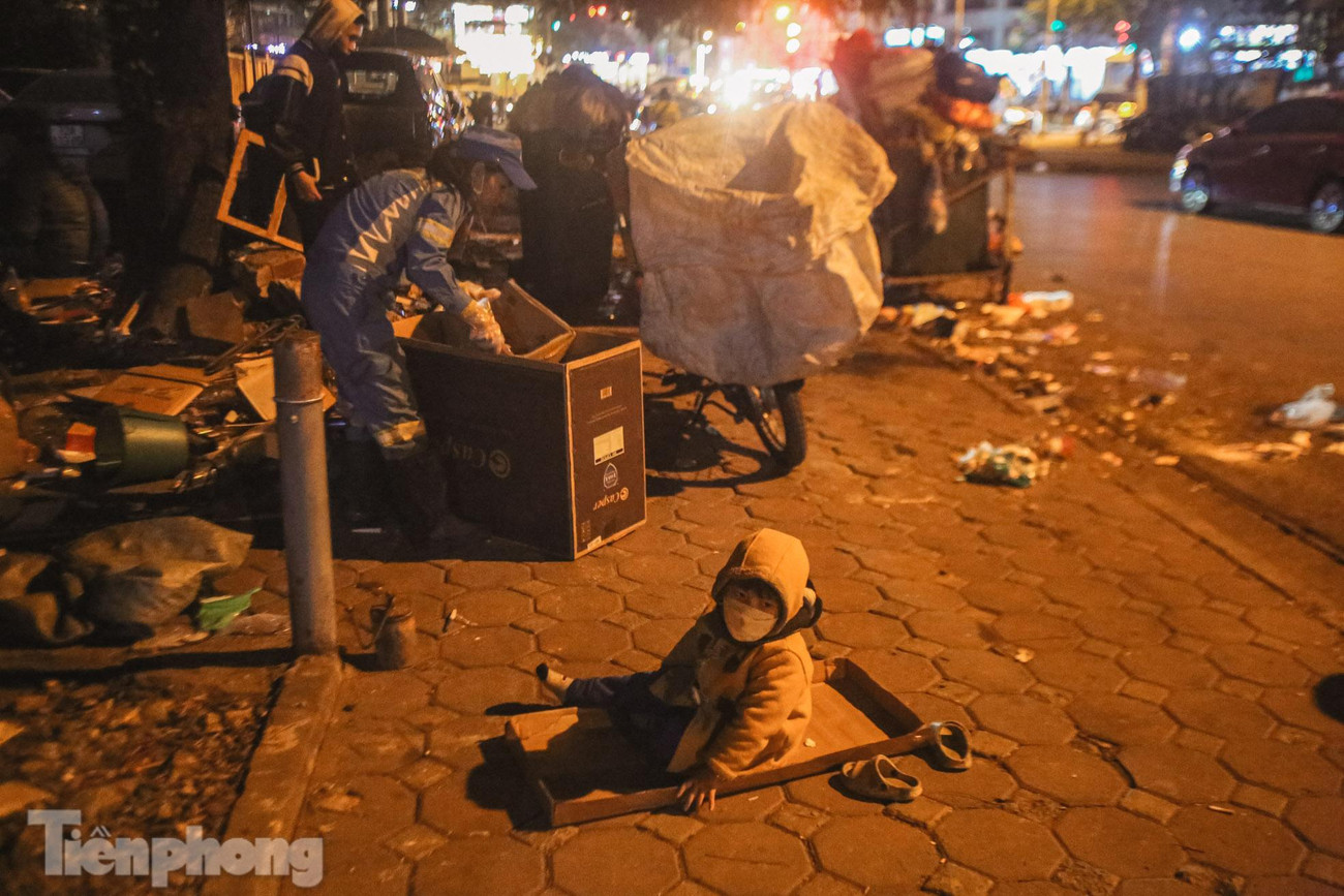 Bé Thóc ngoan ngoãn ngồi giữa bìa cát tông giấy, chơi một mình, đợi mẹ hoàn thành việc thu gom rác giữa đêm giá rét. Bé Thóc ngoan ngoãn ngồi giữa bìa cát tông giấy, chơi một mình, đợi mẹ hoàn thành việc thu gom rác giữa đêm giá rét.