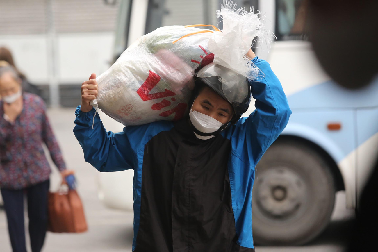 Người đàn ông đội bao đựng đồ mang từ quê lên.