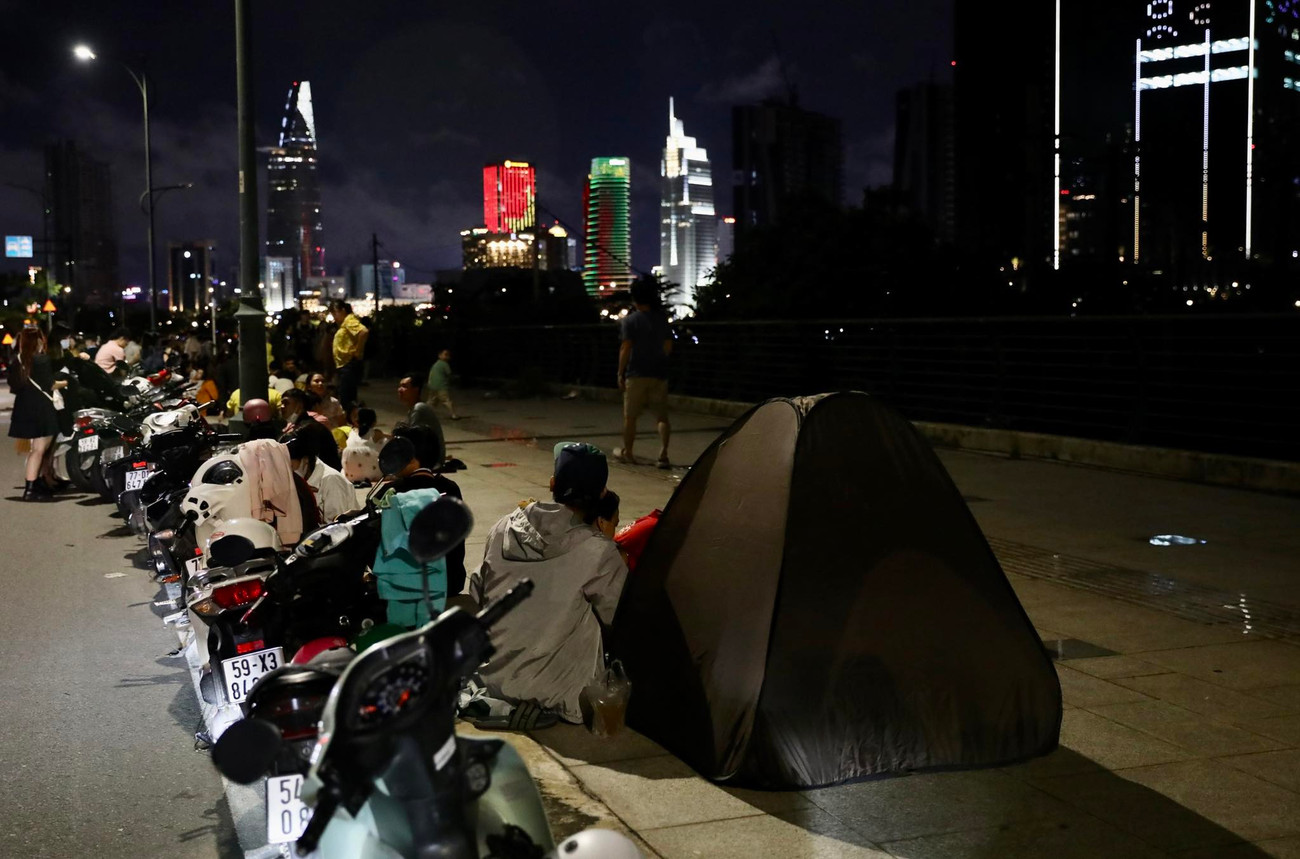 Dựng lều bạt để &quot;xí chỗ&quot; chờ xem bắn pháo hoa. Công viên Bến Bạch Đằng, đối diện vị trí bắn pháo hoa bên kia sông Sài Gòn là khu vực rộng, thoáng và gần khu vực bắn pháo hoa nhất nên luôn được nhiều người lựa chọn. Nhiều gia đình, nhóm bạn trẻ trải bạt, ăn uống trò chuyện chờ đến giờ bắn pháo hoa.