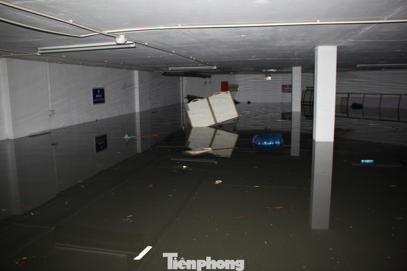 Xe máy, tủ lạnh, chăn màn,... bị ngâm trong nước cả đêm tại một hầm để xe của tòa nhà văn phòng trên đường Doãn Kế Thiện (quận Cầu Giấy, Hà Nội). Đến gần 10h sáng 14/6, mực nước trong hầm để xe này vẫn ở mức 1,3 - 1,5m.
