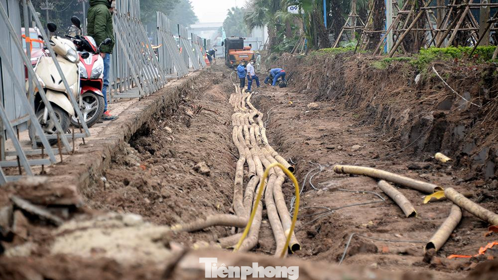 Công nhân của công ty cáp viễn thông đang thực hiện đấu nối để dịch chuyển, trả lại mặt bằng cho việc san lấp phần lòng đường được mở rộng.