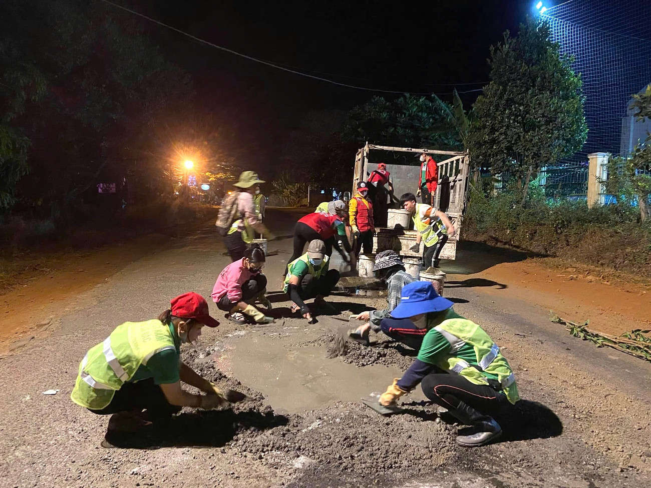 Nhóm thiện nguyện vá đường vui vẻ khi vừa sửa xong một đoạn đường hỏng.