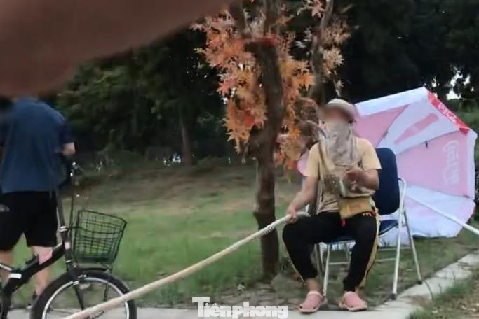 Theo phản ánh của người dân, các lối vào bãi giữa chân cầu Vĩnh Tuy đều đã bị chặn, chỉ còn một lối duy nhất là vòng qua được Thạch Cầu, đi qua cổng Khu sinh thái vườn nhãn Long Biên. Trong ảnh: Người đàn bà căng dây thừng chặn các phương tiện vào bãi giữa chân cầu Vĩnh Tuy.