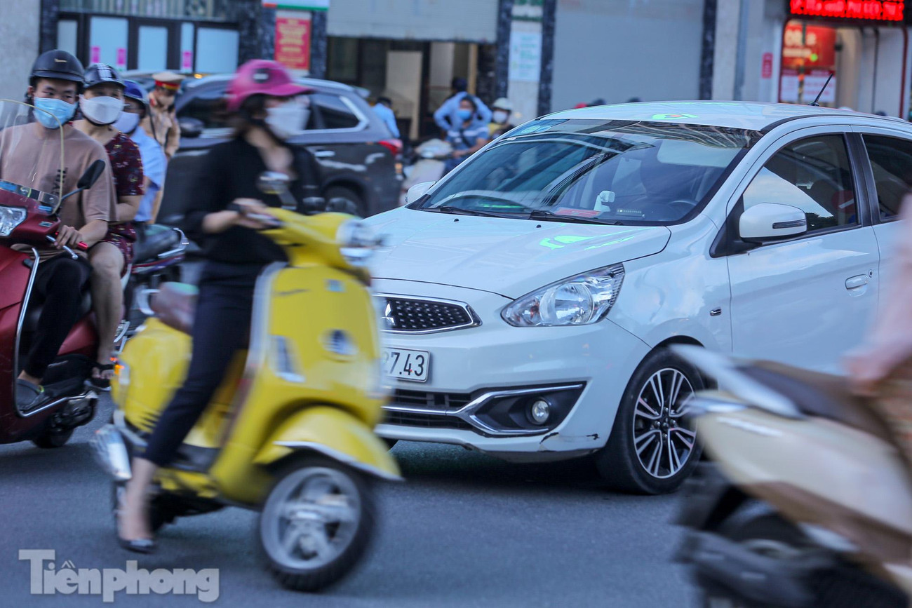 Một ô tô phải nhường dòng phương tiện xe máy băng qua đường.