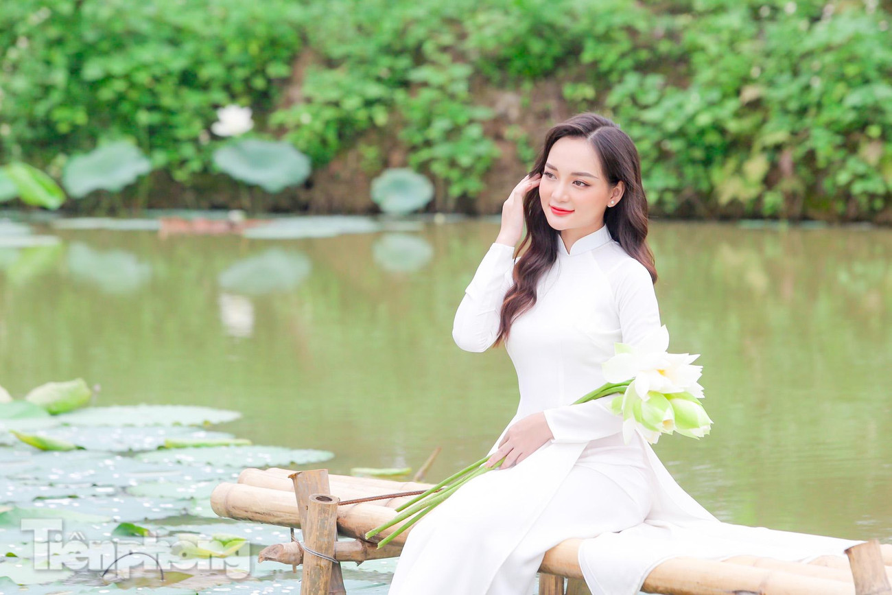 Thiếu nữ xinh đẹp thả dáng với áo dài trắng bên cạnh hoa sen.