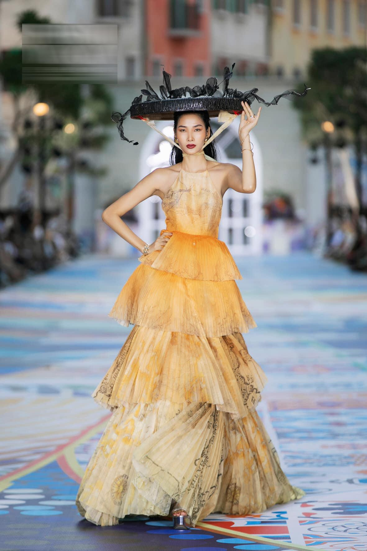 Hoàng Thùy khoe dáng đầy quyến rũ và ấn tượng trên sàn catwalk trong bộ váy kiểu cổ yếm có thiết kế xếp tầng độc đáo, kết hợp với nón quai thao cách điệu.