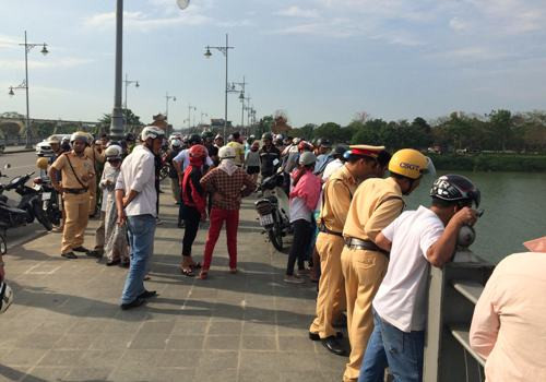 Người dân tập trung trên cầu theo dõi lực lượng chức năng tìm kiếm nam thanh niên. Ảnh: Võ Thạnh. 