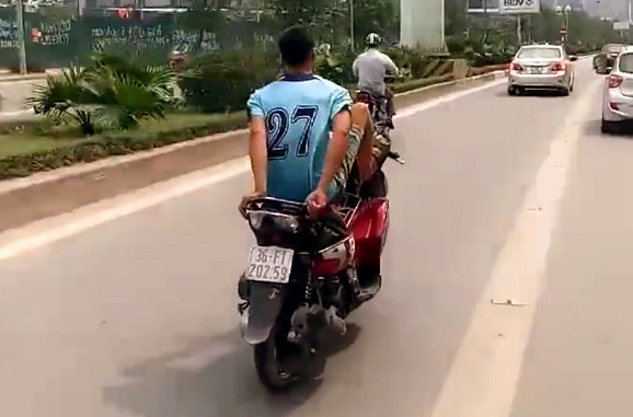 Nam thanh niên trổ tài điều khiển xe máy bằng chân. (Ảnh cắt từ clip)