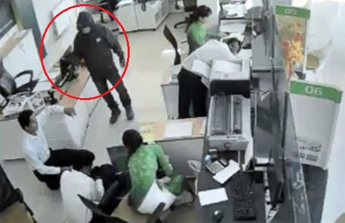 Tên cướp liên tục nạt nộ, dọa bắn các nhân viên, yêu cầu gom tiền bỏ vào 2 túi xách. Ảnh: Cắt từ video. 