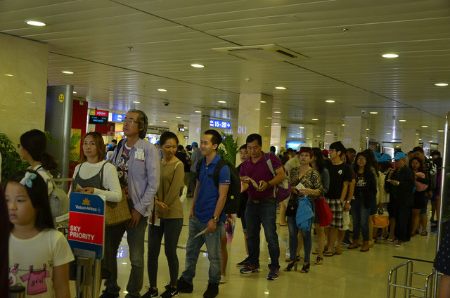 Từng đoàn khách xếp hàng dài nối đuôi nhau chờ ra máy bay