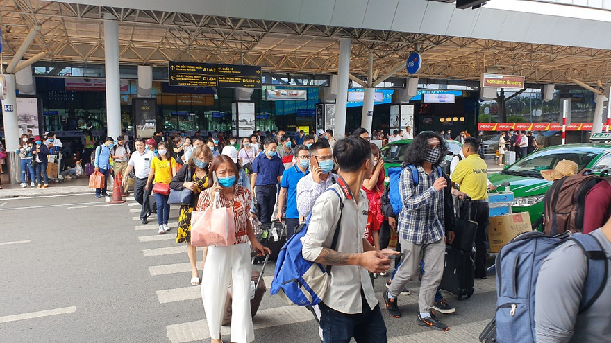 Hành khách đi bộ cắt ngang các làn ô tô trước ga quốc nội.