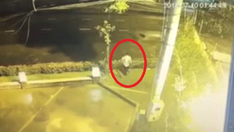 Nam công nhân đi bộ qua quốc lộ sau khi trộm tiền.