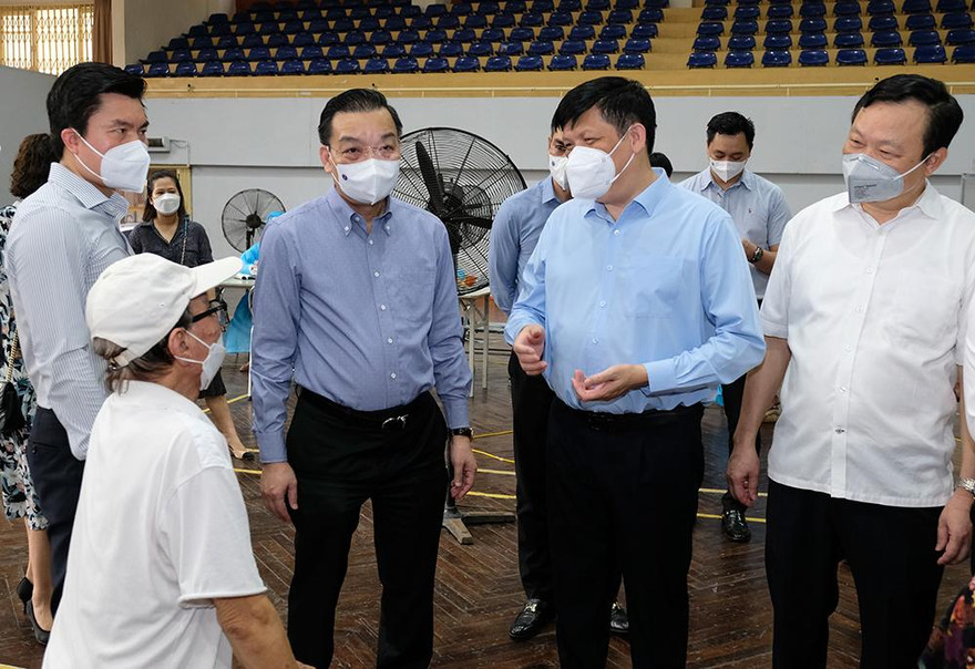 Bộ trưởng Nguyễn Thanh Long trò chuyện với người tiêm chủng vaccine tại điểm tiêm chủng trên phố Trịnh Hoài Đức, TP Hà Nội. Ảnh: BYT