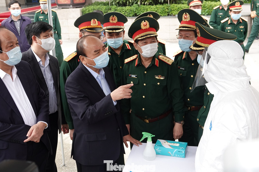 Thủ tướng Nguyễn Xuân Phúc trò chuyện với nhân viên xe xét nghiệm cơ động của Viện Y học dự phòng Quân đội khi tới làm việc với BCĐ phòng chống dịch COVID-19 của Bộ Quốc phòng, ngày 22/3